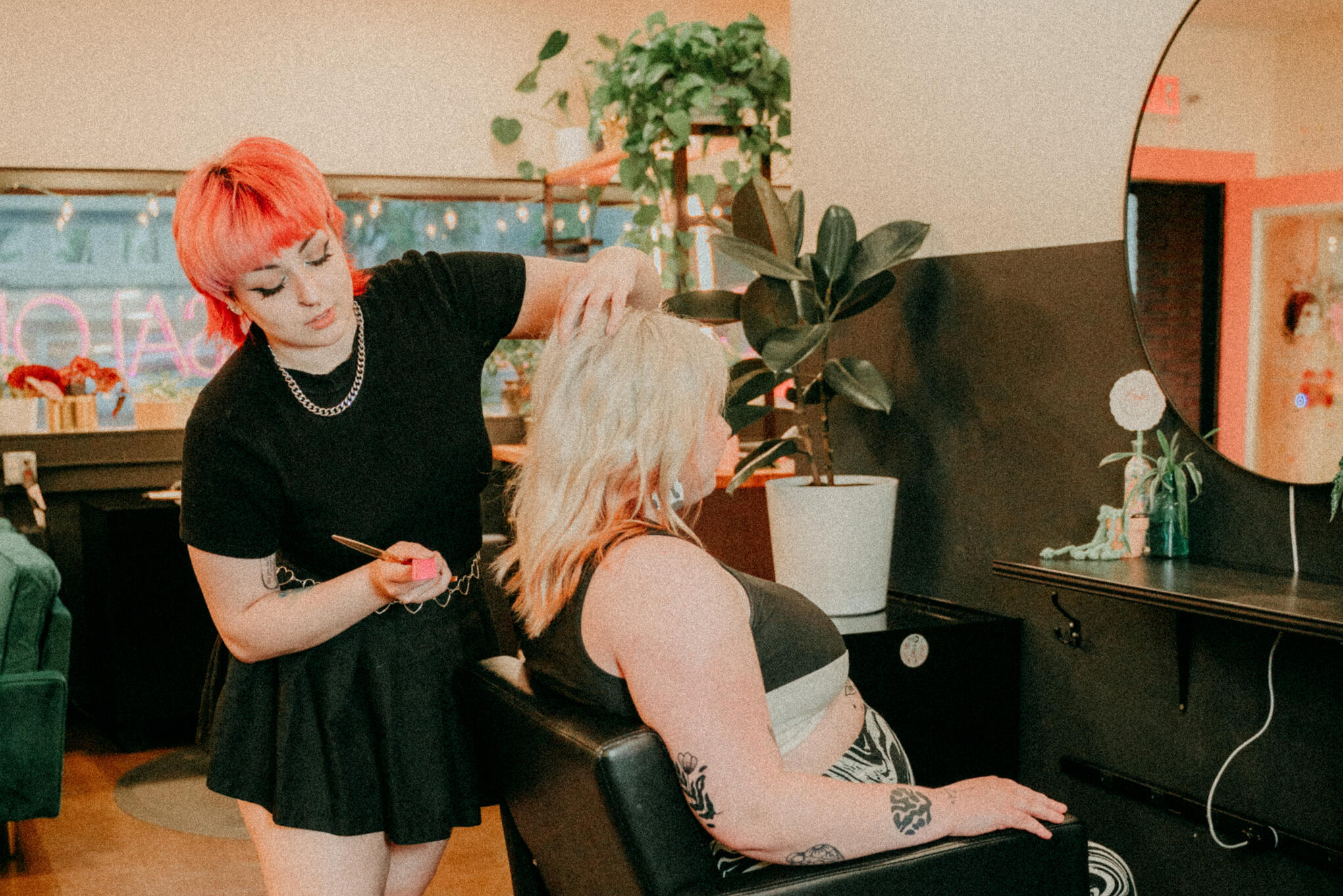 A hair stylist stands behind a fat client in a salon chair.